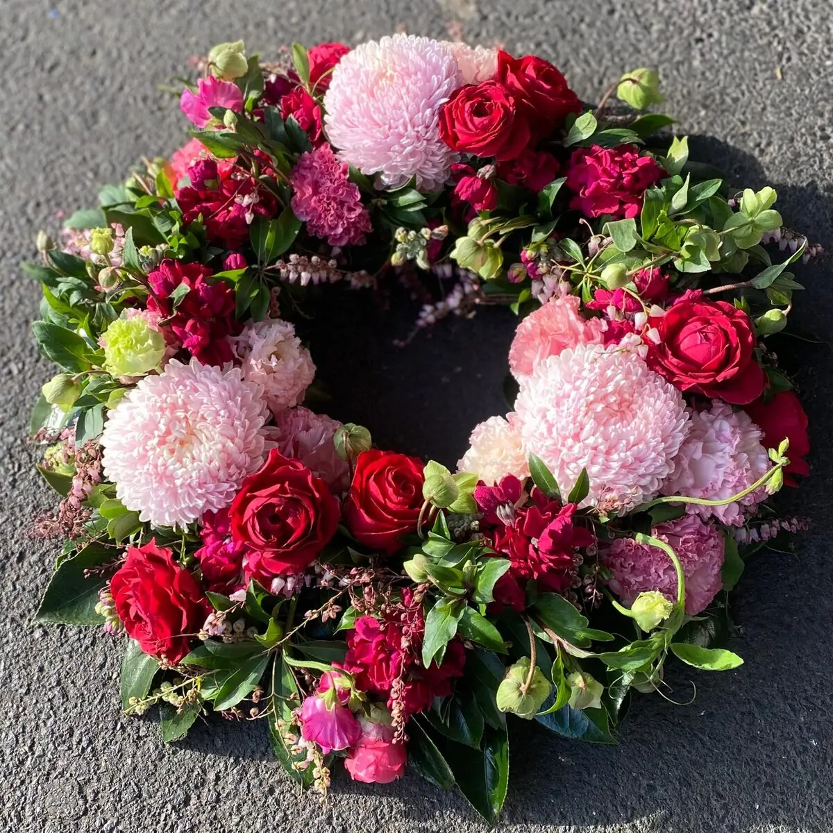 Funeral wreath of red roses and pink blooms
