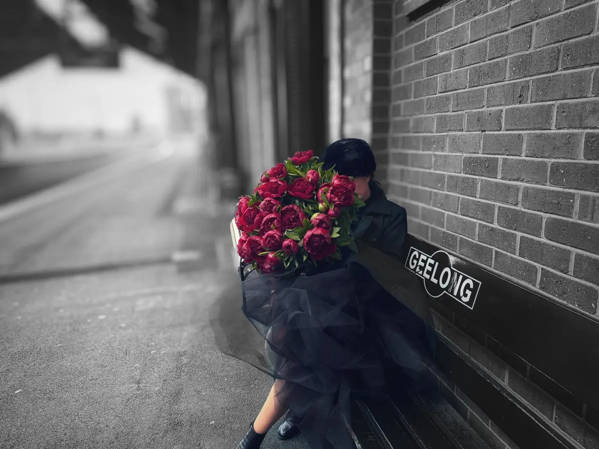 Seated on the Geelong station bench with an armful of red peonies