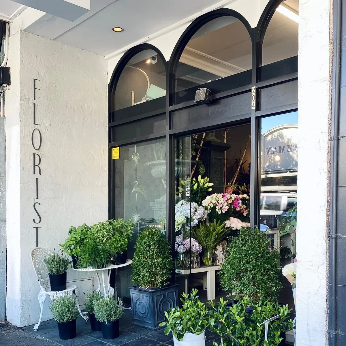 The Red Poppy shopfront with arched windows and potted plants on the footpath